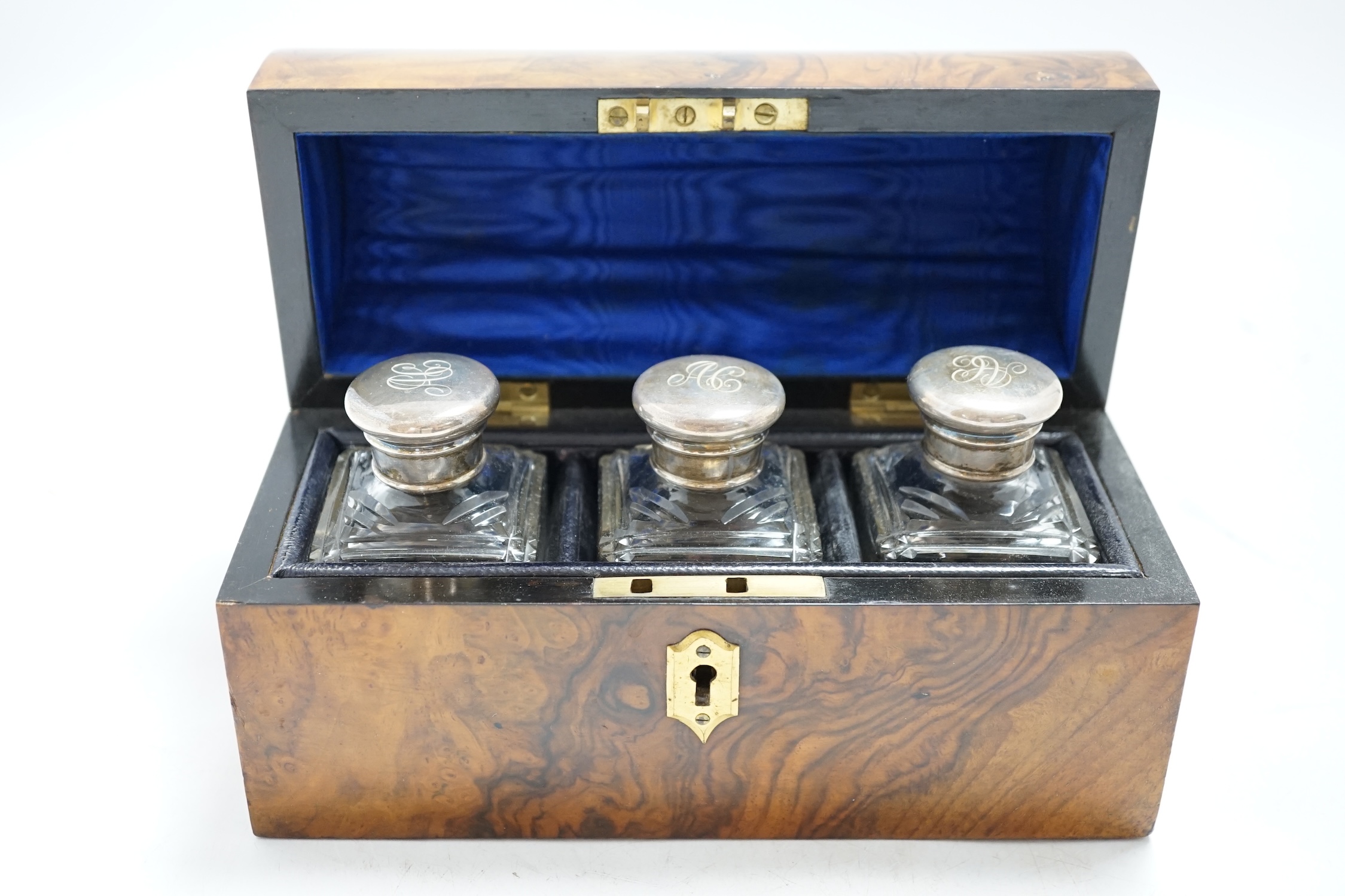 A Victorian walnut dome topped scent bottle case, fitted with three glass bottles with plated mounts, case 20.5cm wide. Condition - metal mount to dome top at the front missing, with minor damage to veneer